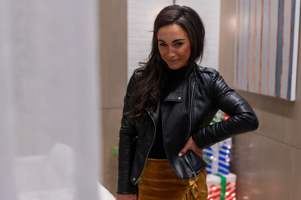 Model wearing black leather jacket and velvet skirt.